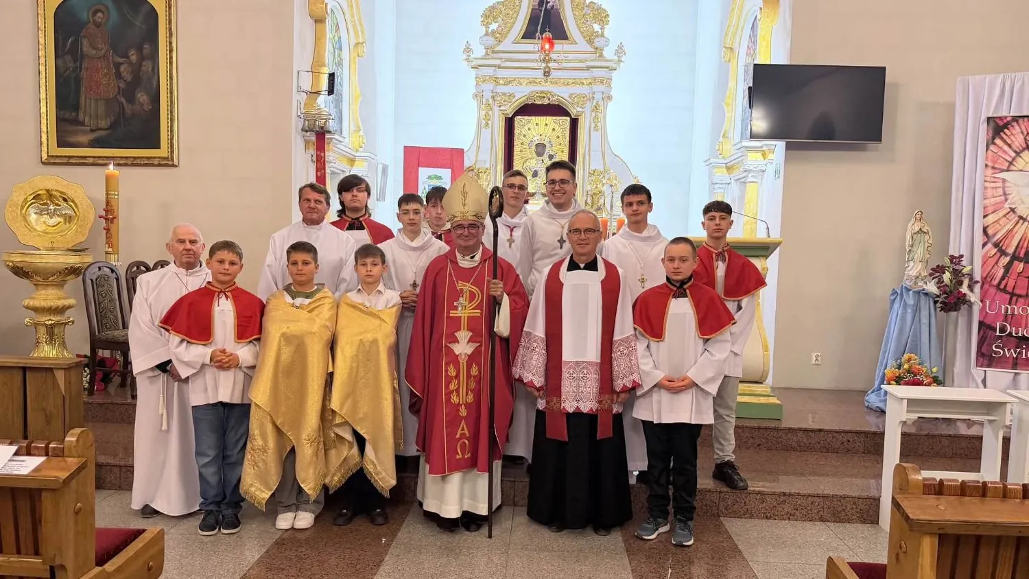Ministranci i lektorzy parafii z ks. bp. Szymonem Stułkowskim i ks. proboszczem przed ołtarzem kościoła w Korzeniu